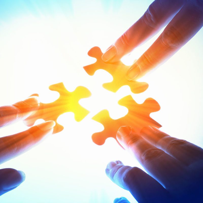 Fingers pushing jigsaw peices together