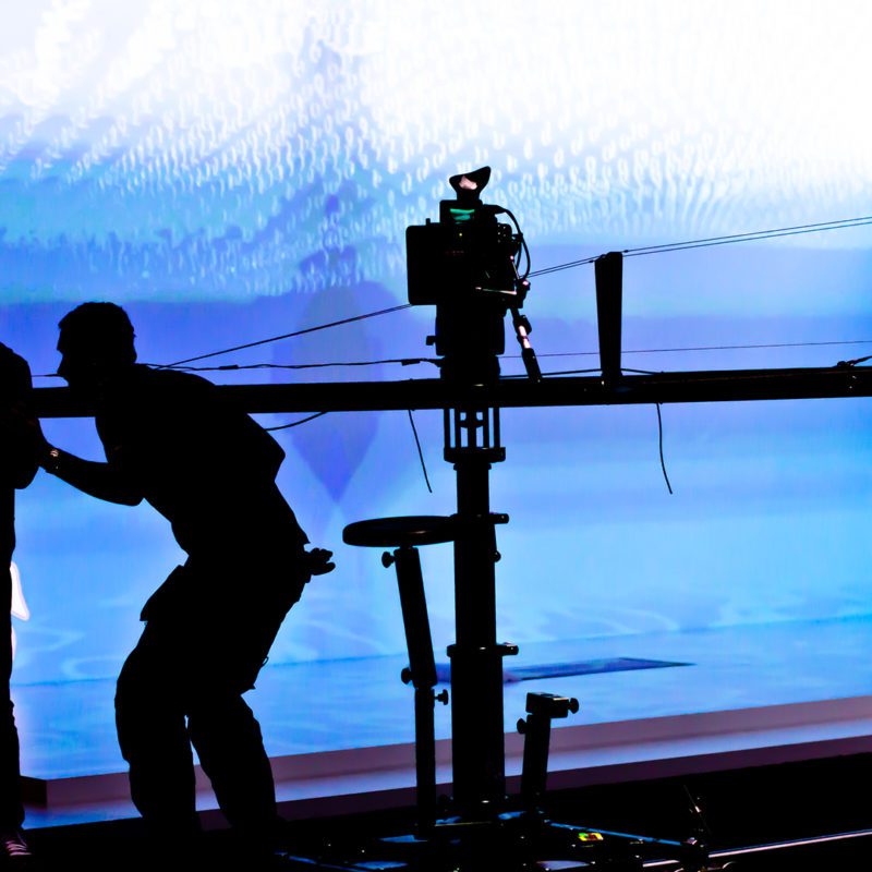 Film crew silhouetted in front of stage